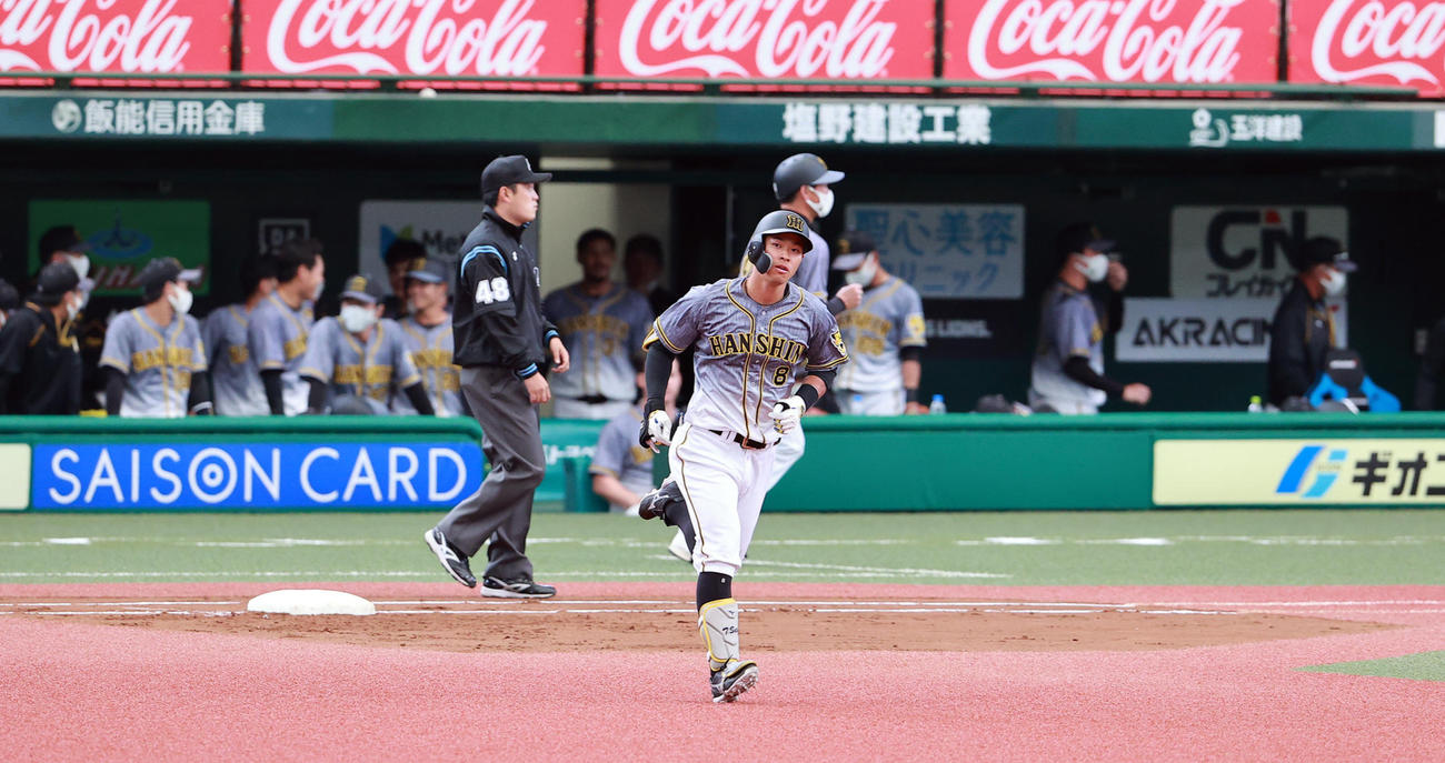 2回表阪神無死、佐藤輝は右越えソロ本塁打を放ち、ざわつく阪神ベンチを背に一塁を回る（撮影・浅見桂子）