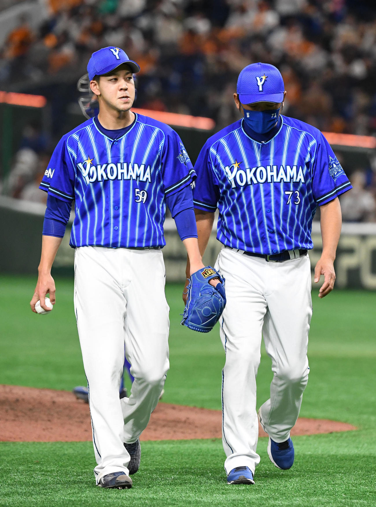 巨人対DeNA　6回表途中、治療のためベンチへ引き揚げる平良（左）。右は木塚コーチ（撮影・横山健太）