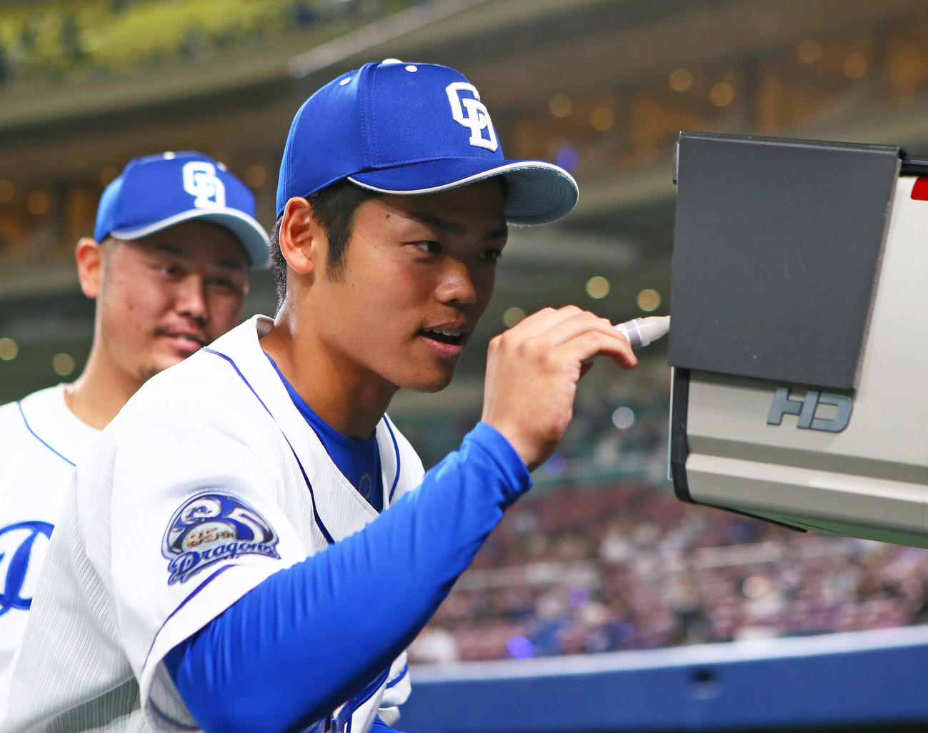 中日対巨人　テレビカメラ越しにメッセージを書き込む中日の根尾、後方は鈴木（撮影・足立雅史）