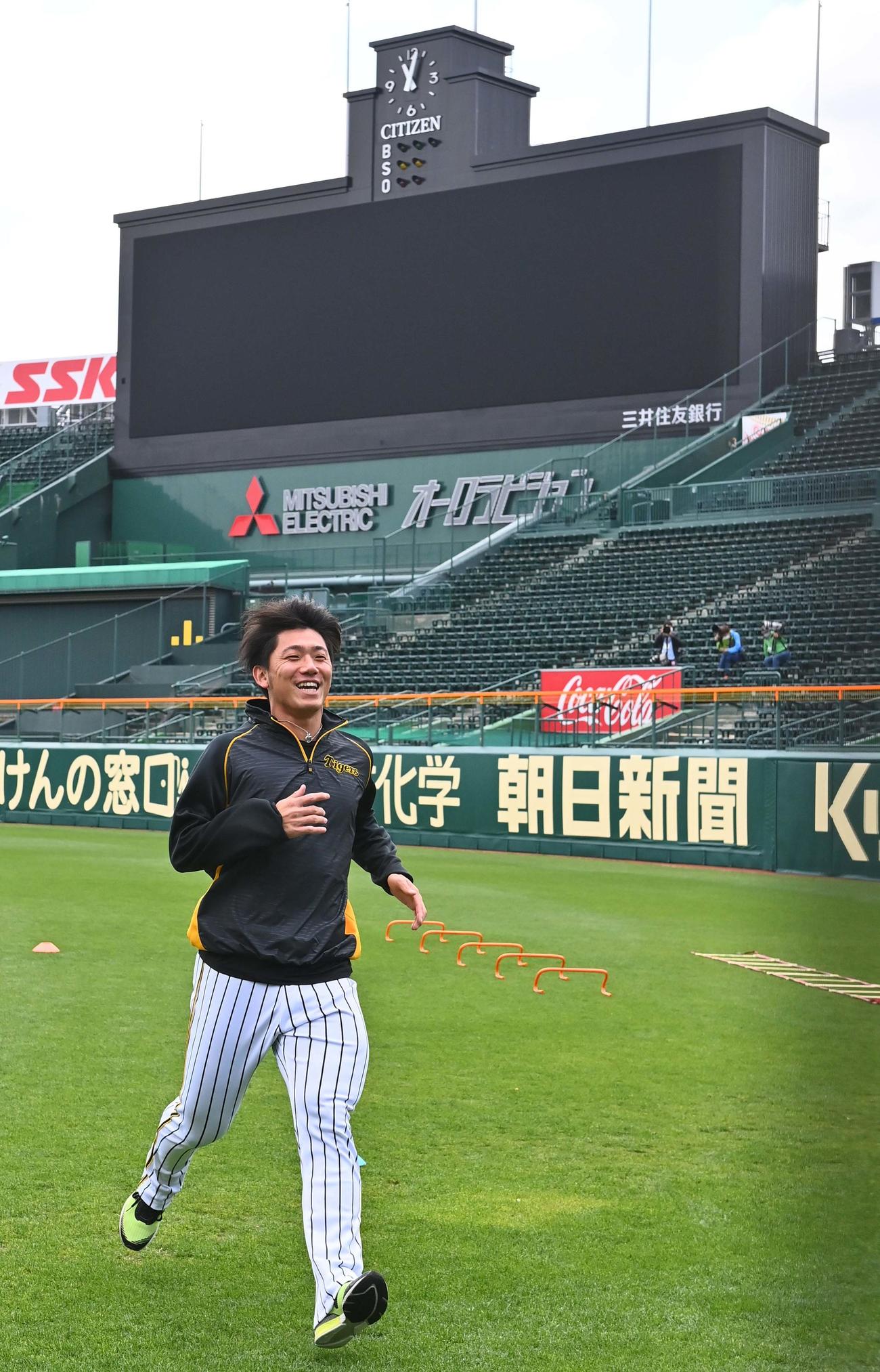 甲子園球場での初登板を控える阪神伊藤将司はスコアボードを背に笑顔でダッシュする（撮影・上田博志）