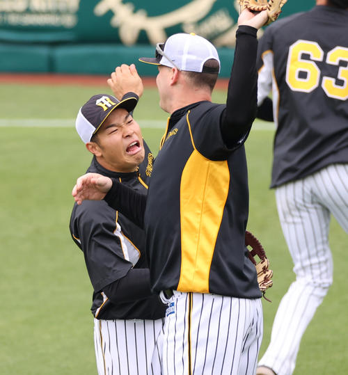 阪神対巨人　練習でサンズ（手前）とおどけた表情を見せ合う佐藤輝（撮影・清水貴仁）