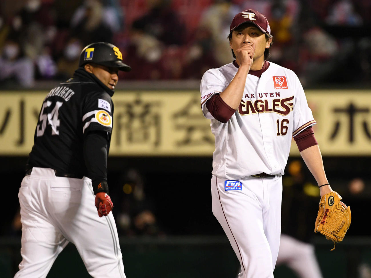 楽天対ソフトバンク　6回表を無失点に抑え、手を暖めながらベンチへ引きあげる楽天涌井（右）。左はソフトバンクのデスパイネ（撮影・横山健太）