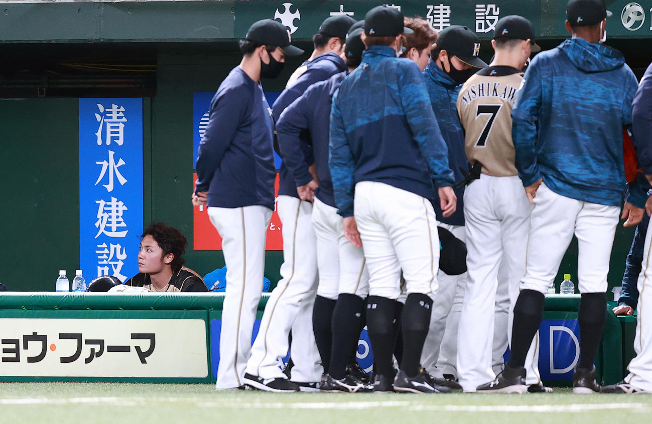西武対日本ハム　4回表日本ハムの攻撃前、円陣を組む選手の奥で悔しそうな表情の伊藤（左）（撮影・浅見桂子）