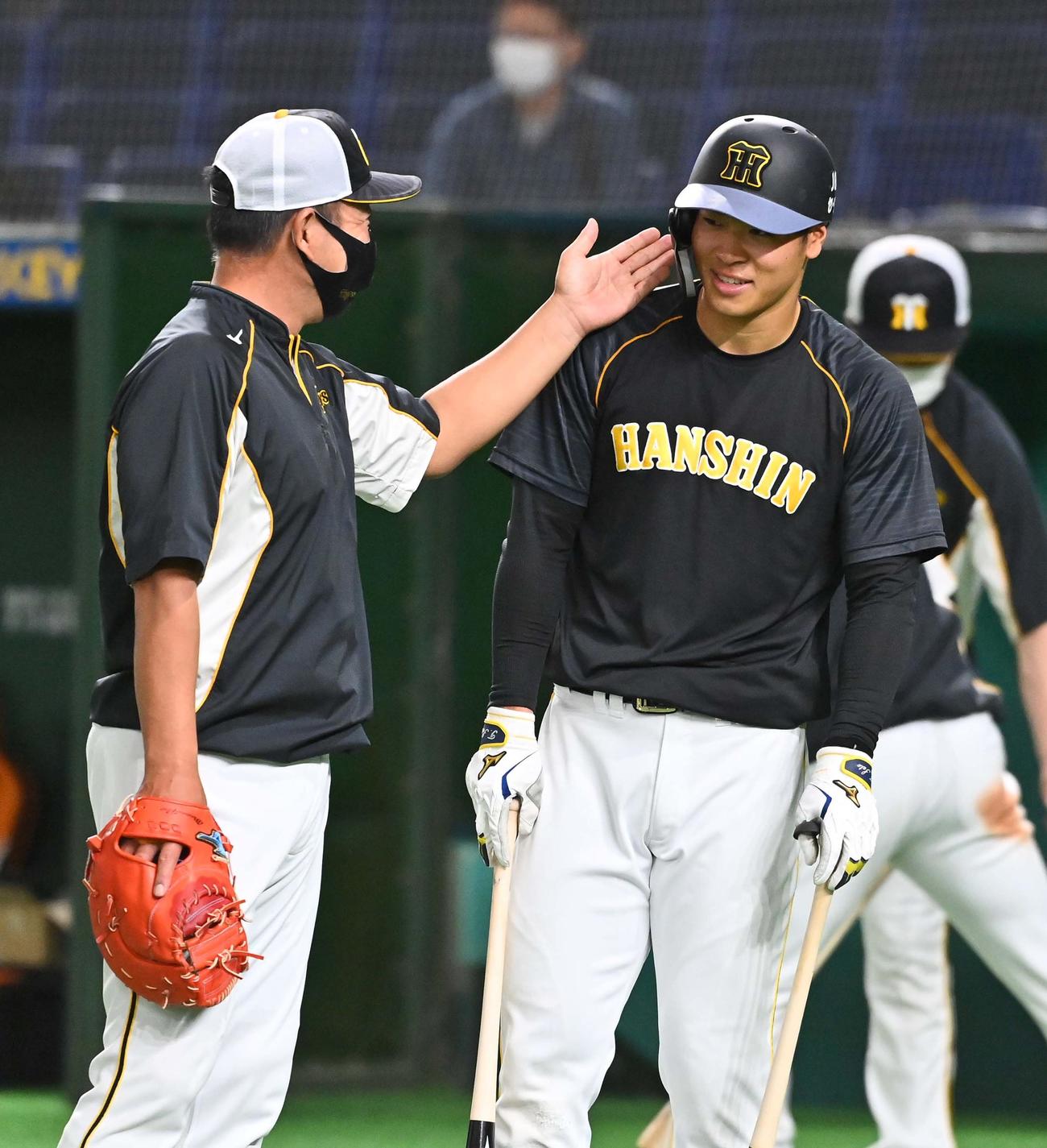 巨人対阪神　佐藤輝明（右）の首にチョップして打撃指導を終える井上一樹ヘッドコーチ（撮影・上田博志）
