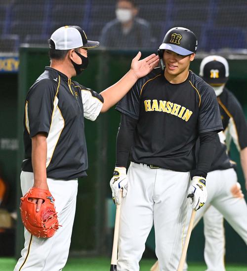 巨人対阪神 佐藤輝明(右)の首にチョップして打撃指導を終える井上一樹ヘッドコーチ(撮影・上田博志)