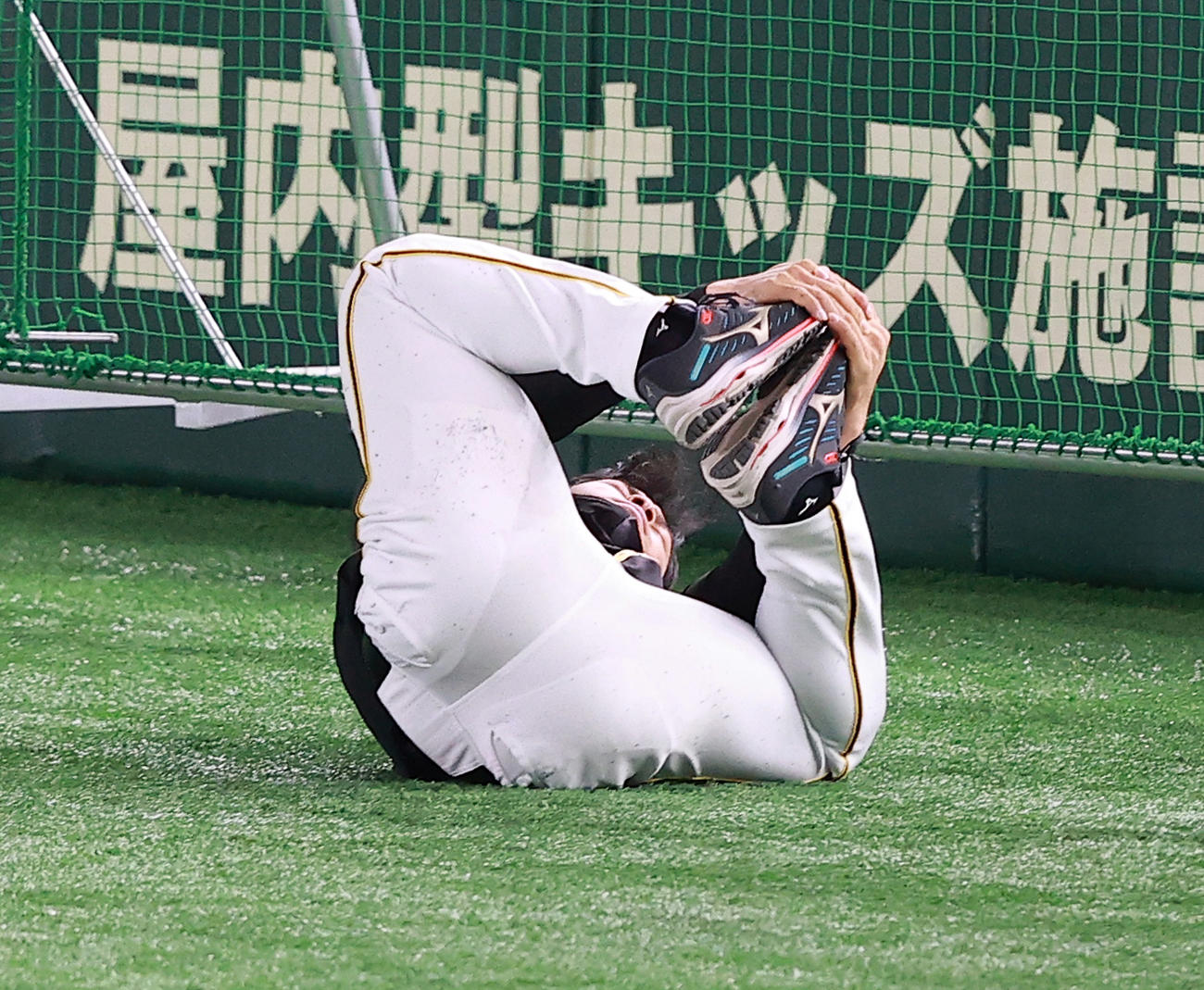巨人対阪神　試合前練習で、ストレッチしながらゴロゴロと回る佐藤輝（撮影・浅見桂子）