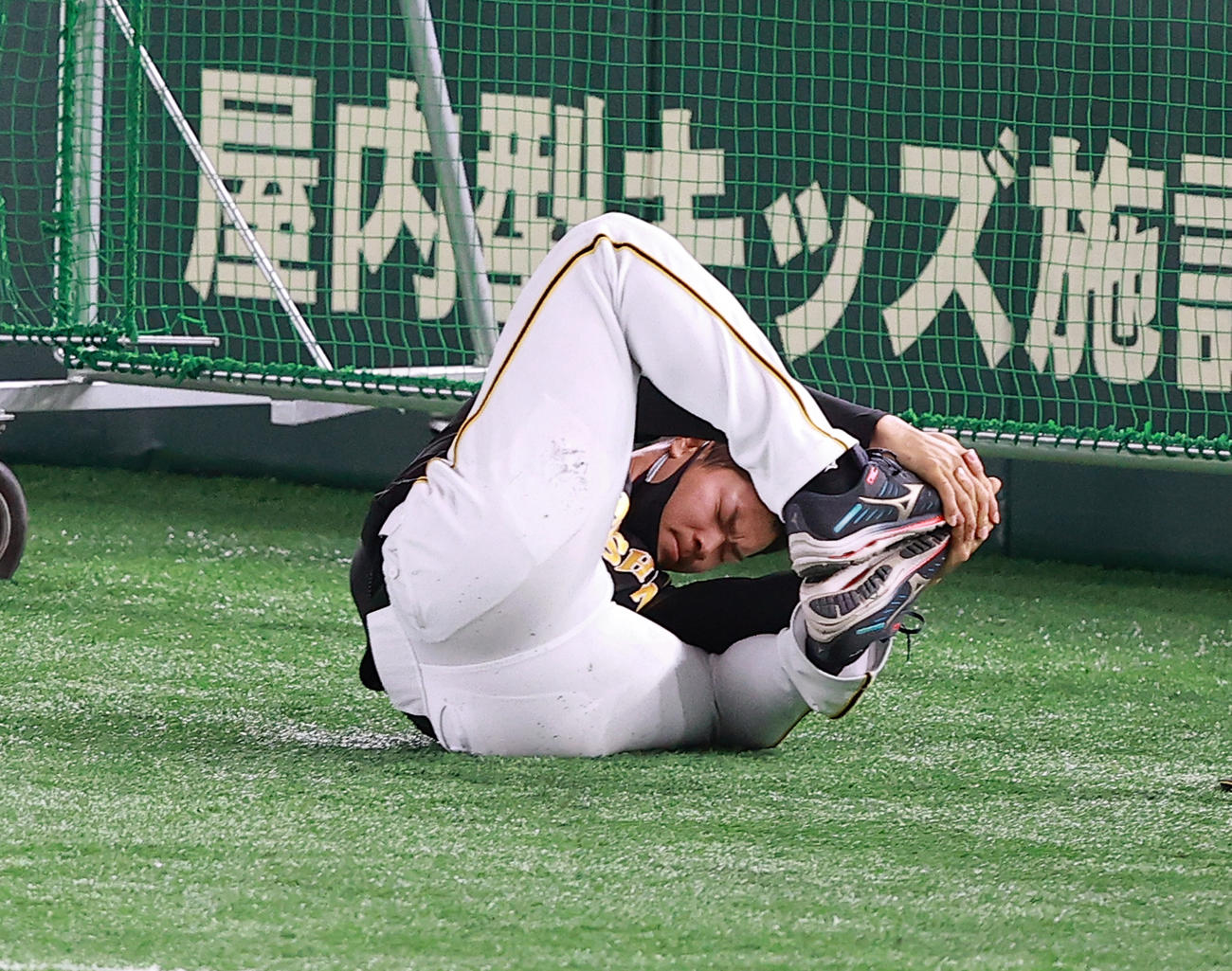 巨人対阪神　試合前練習で、ストレッチしながらゴロゴロと回る佐藤輝（撮影・浅見桂子）