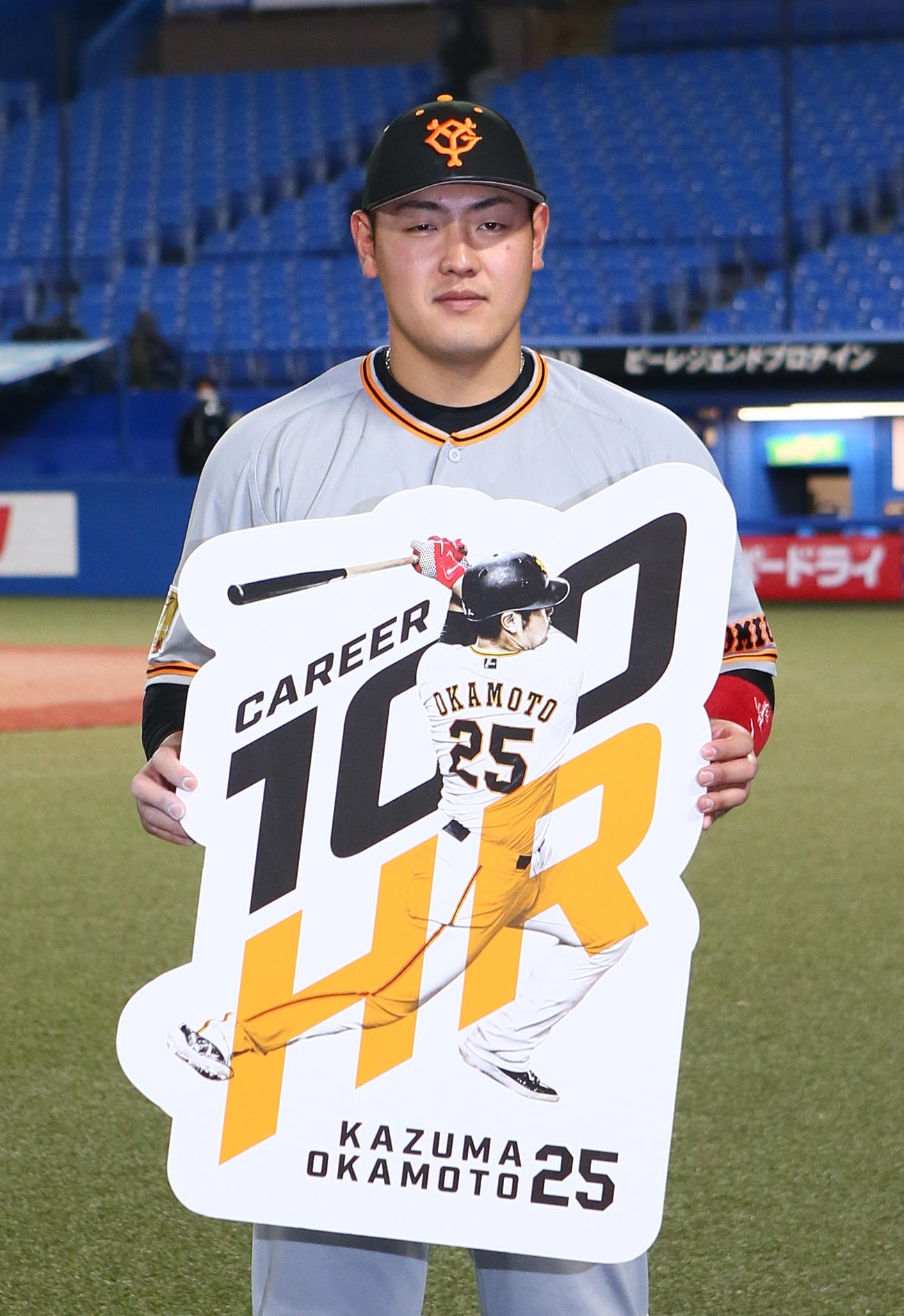 ヤクルト対巨人　通算100号本塁打の巨人岡本和はボードを手に笑顔を見せる（撮影・足立雅史）