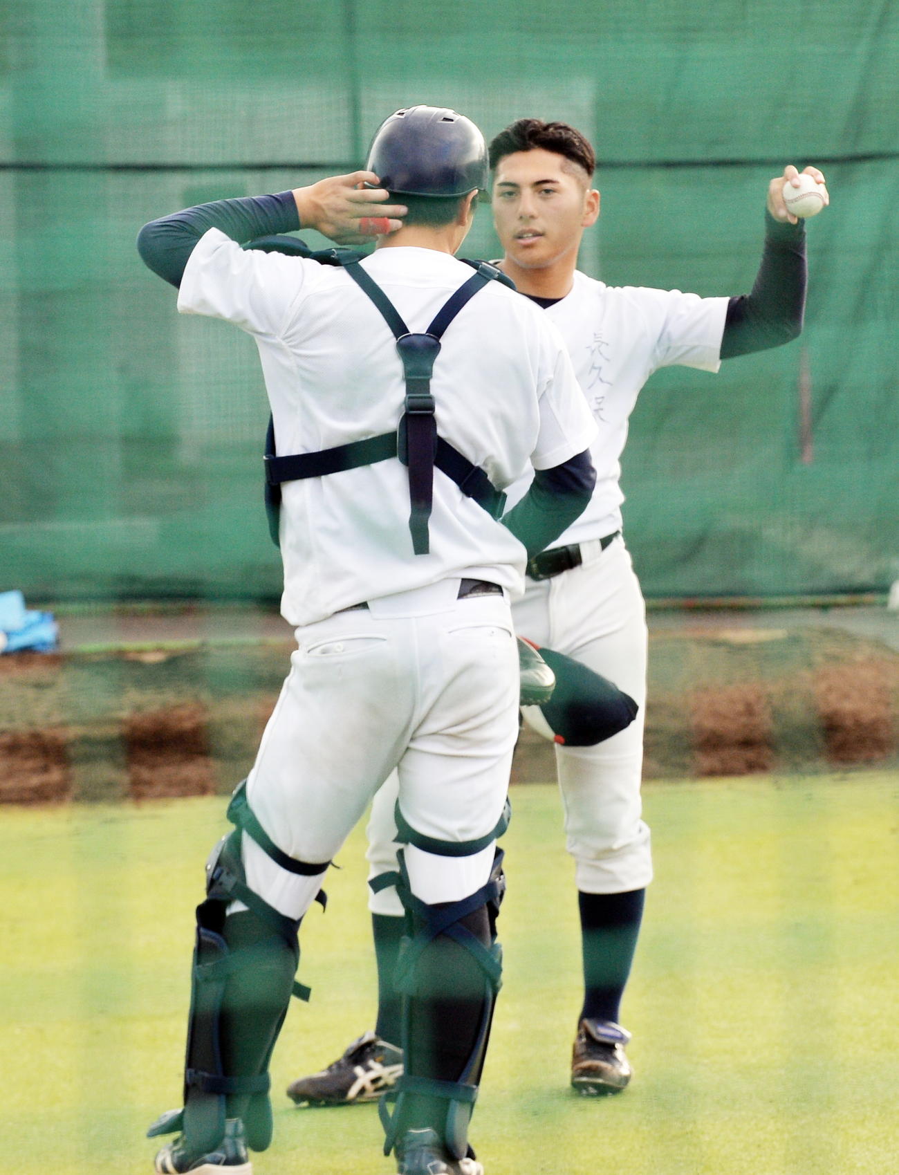 ブルペン投球後、捕手と意見交換する仙台大・長久保