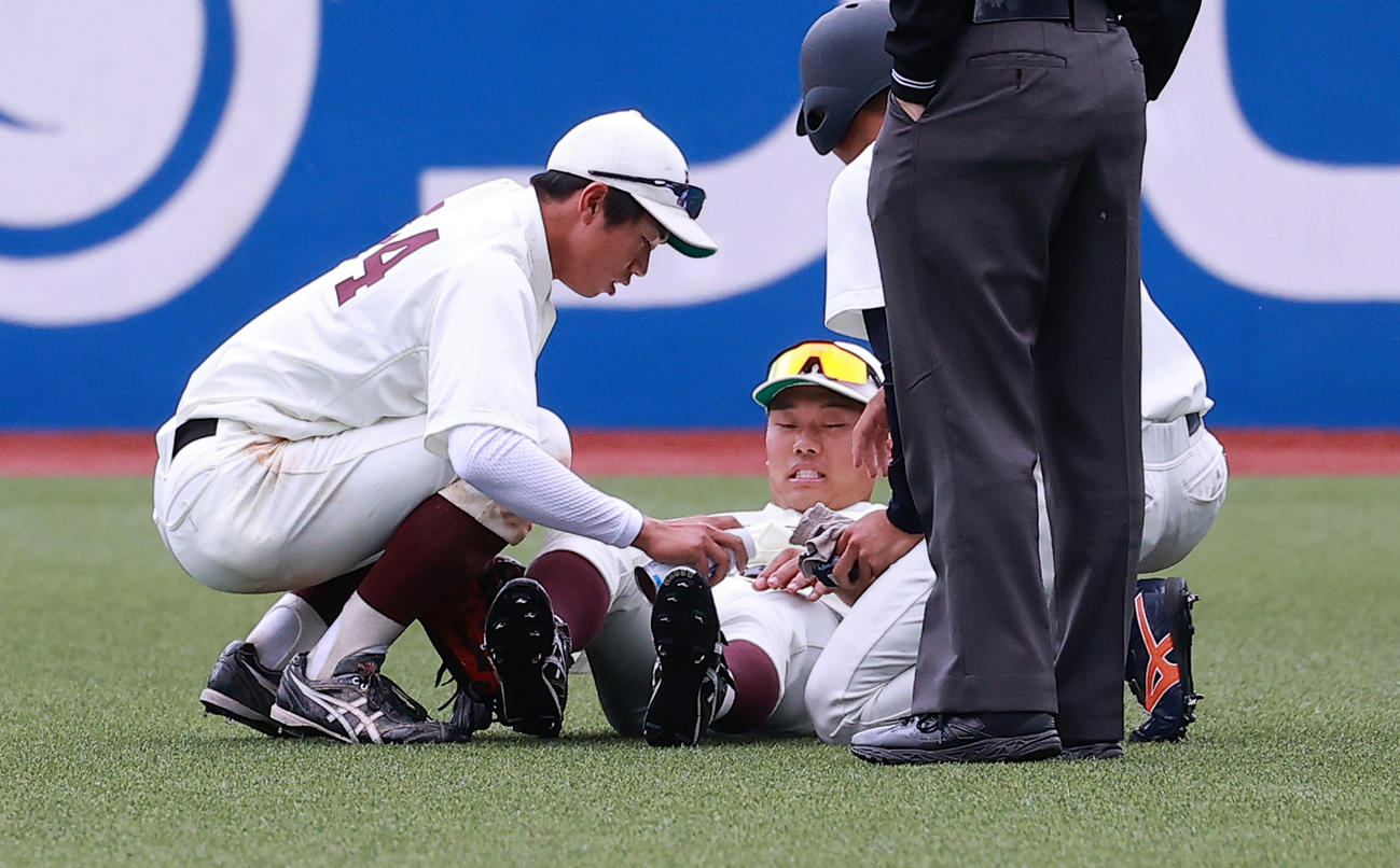 早大対法大　7回裏法大2死、小池の打球を追って左ひざを負傷した蛭間（中央）は痛そうな表情（撮影・浅見桂子）