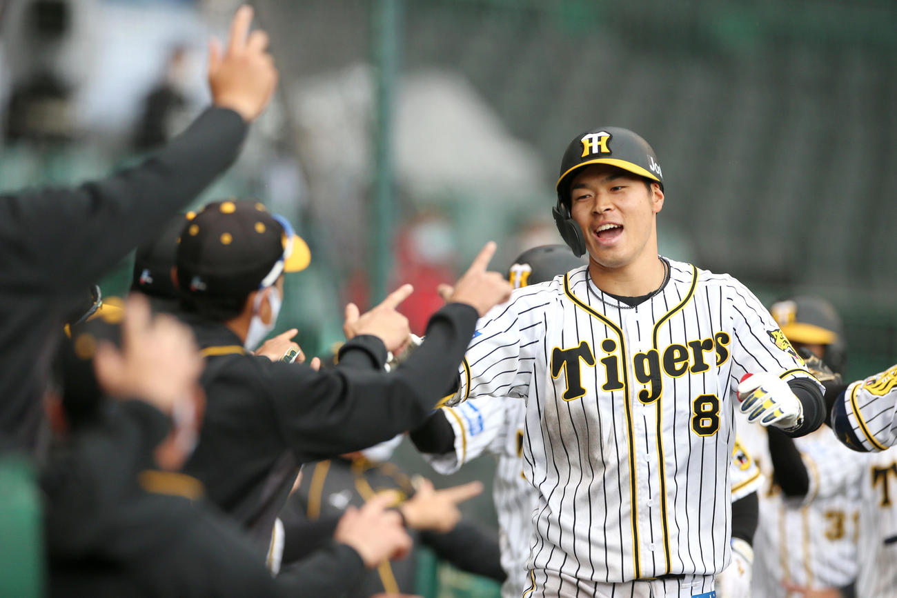 阪神対広島　5回裏阪神無死満塁、佐藤輝は右越え満塁本塁打を放ちベンチの出迎えに笑顔を見せる（撮影・上山淳一）