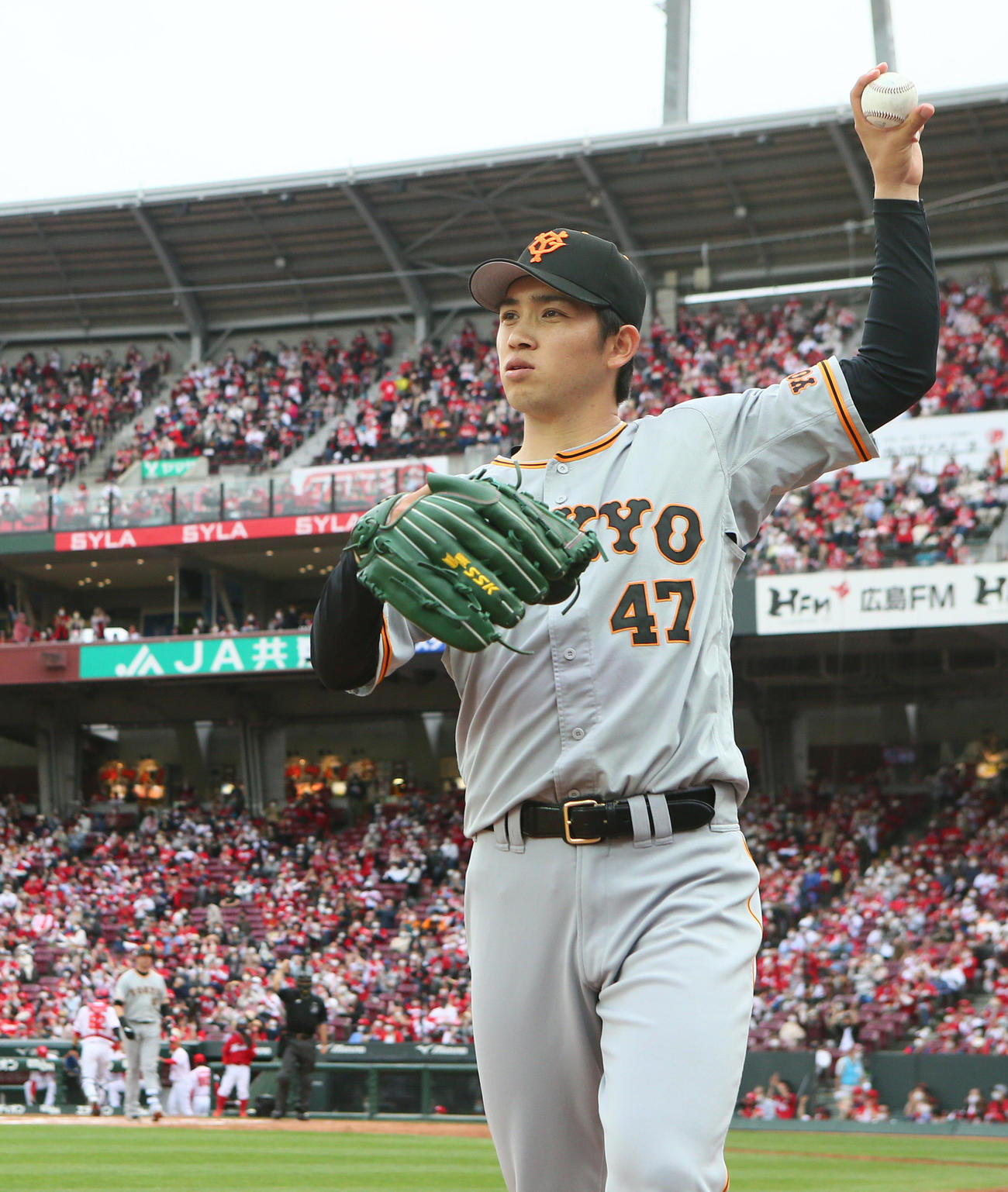 広島対巨人　7回表巨人2死二、三塁、スモーク（後方）が空振り三振に倒れる中、表情を変えず投球練習する高橋（撮影・足立雅史）