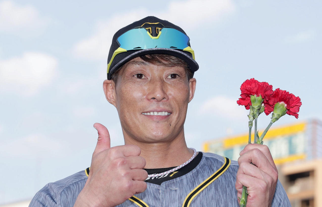 試合後、カーネーションを手に笑顔でサムアップポーズを決める阪神糸井（撮影・前田充）