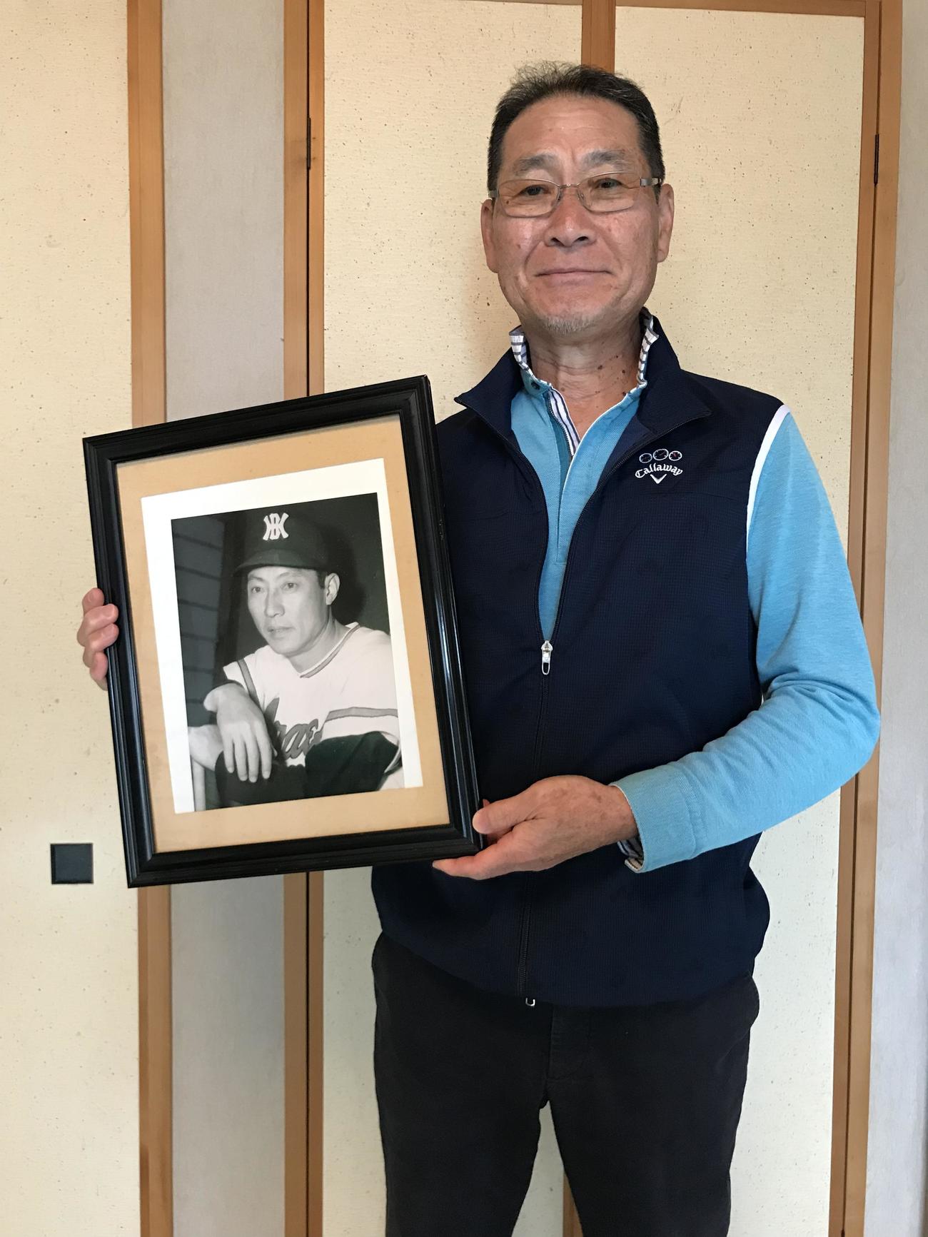 在りし日の戸倉勝城氏の写真を持つ三男・恒城氏