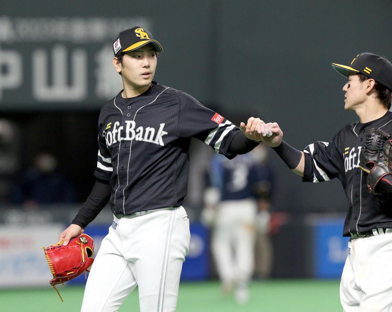 日本ハム対ソフトバンク　6回裏を無失点に抑えグータッチを交わしながらベンチに戻るソフトバンク石川（撮影・佐藤翔太）