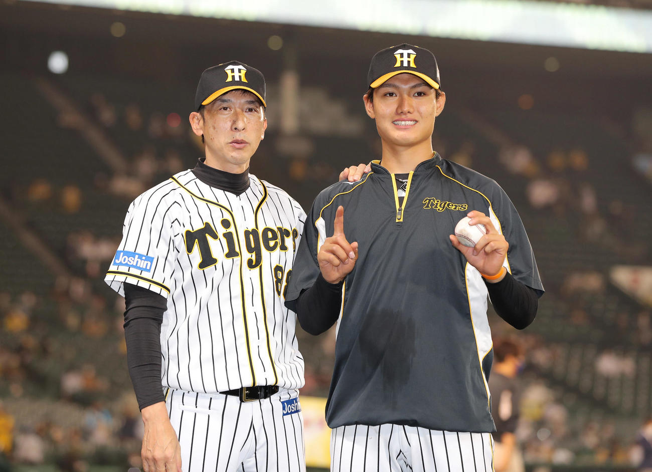 阪神対ヤクルト　プロ初勝利を挙げ、勝利球を手に笑顔でポーズを決める阪神西純。左は祝福する矢野監督（撮影・前田充）