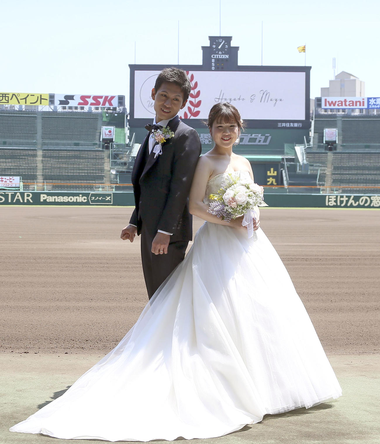 甲子園球場で笑顔いっぱいにウェディングフォトする堀北勇人さんと新婦の麻由さん（撮影・上山淳一）