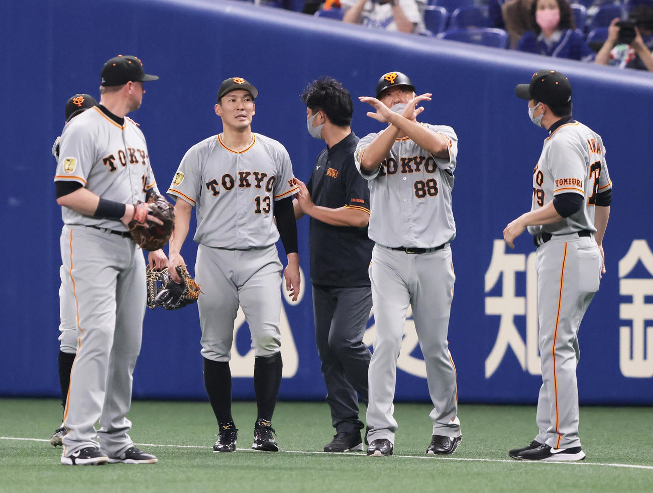 中日対巨人　3回裏中日1死二塁、守備の際に負傷した巨人右翼手梶谷（中央左）を見てベンチに×印を出す後藤コーチ（同右）（撮影・足立雅史）
