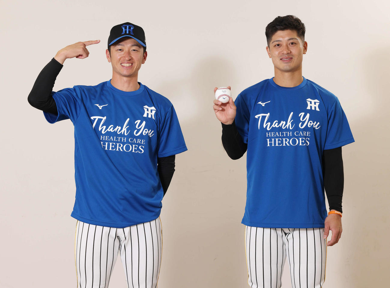 6月18日、「HEALTH CARE HEROES GAME Supported by Joshin」として開催される阪神対巨人戦で使用される、医療従事者への感謝を伝える「青色」にデザインされたウエアを着用する近本（左）と坂本（球団提供）
