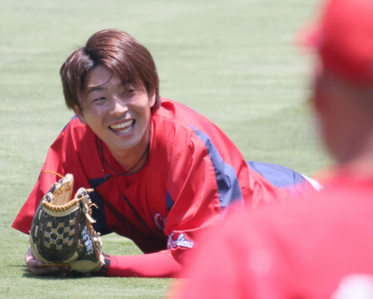 キャッチボール中、ボールを取り損ねて転び、笑顔をみせる大瀬良（撮影・加藤孝規）