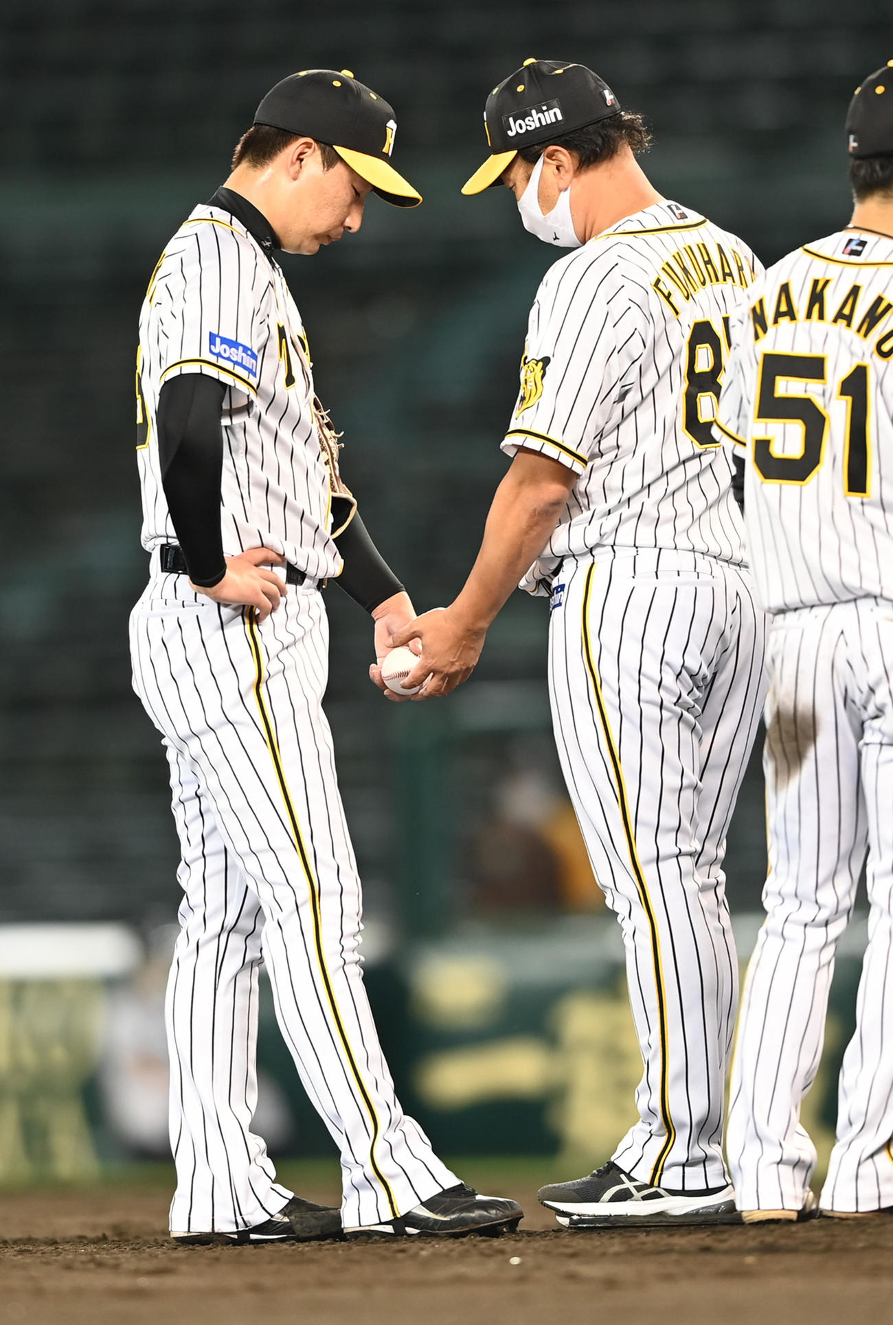 阪神対オリックス　8回、紅に2点本塁打を打たれ交代する岩崎優（左）は無念の表情で福原コーチにボールを渡す（撮影・前岡正明）