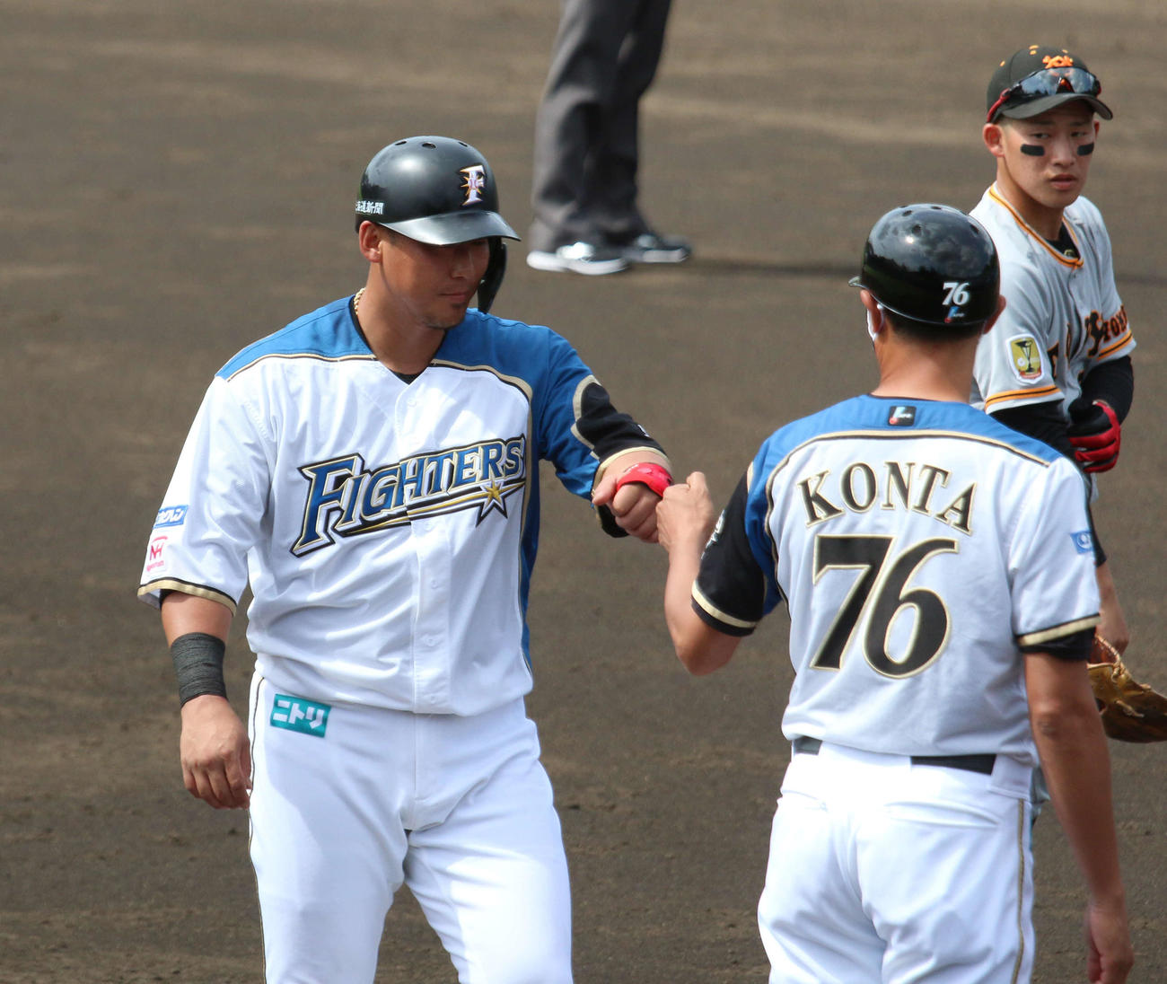 日本ハム対巨人　4回裏日本ハム1死一、二塁、三進した中田（左）は紺田三塁ベースコーチとグータッチ（撮影・木下大輔）