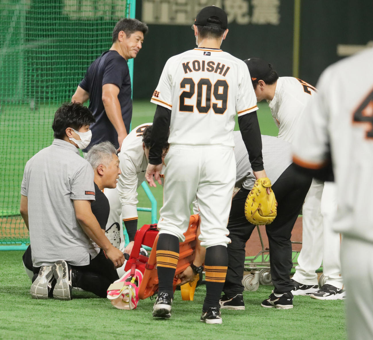打撃投手を行っていた際、ケージに跳ね返った打球が頭に当たり座り込む巨人後藤コーチ（左から2人目）（撮影・足立雅史）