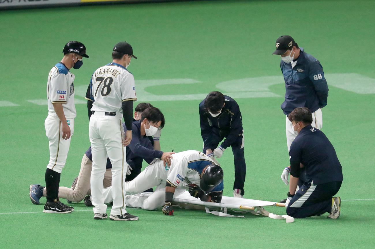日本ハム対阪神　3回裏日本ハム1死満塁、三ゴロを放ち一塁を駆け抜けた後、その場で動けなくなり運ばれる中田（撮影・佐藤翔太）