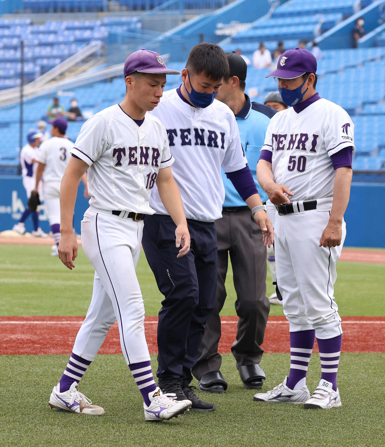 天理大対東農大北海道オホーツク　6回裏東農大北海道オホーツク無死一塁、守屋俊の打球を左足に当て、治療のためにベンチに引き揚げる井奥（左）。右端は藤原監督（撮影・河野匠）