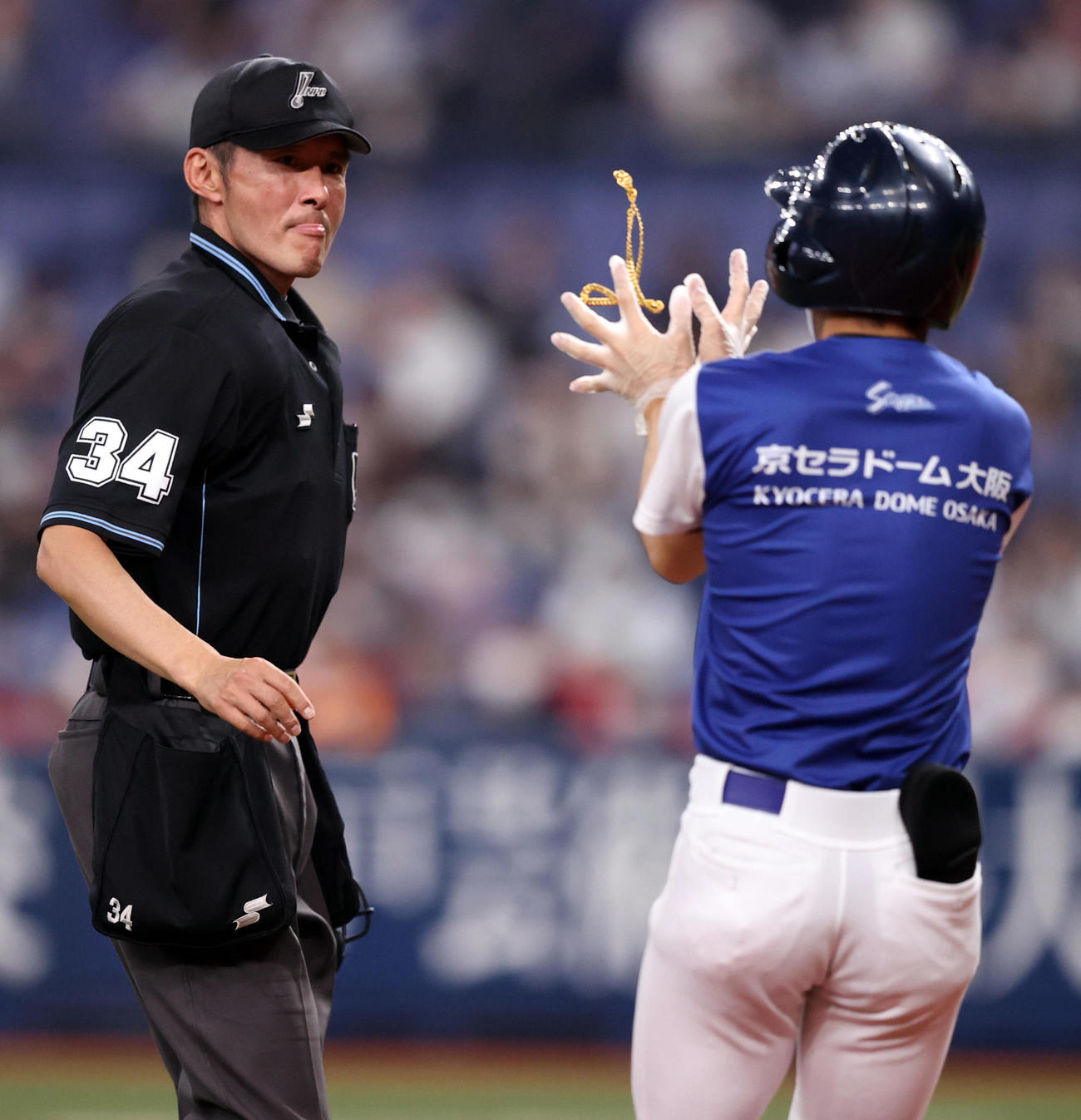 オリックス対巨人　4回裏オリックス2死二塁、サンチェスのネックレスを受け取った後、スタッフに渡す土山球審（撮影・狩俣裕三）