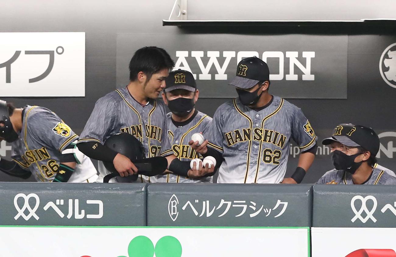 日本ハム対阪神　ベンチに戻ってきた小野寺は更に植田から3個目の記念球を差し出される（撮影・黒川智章）