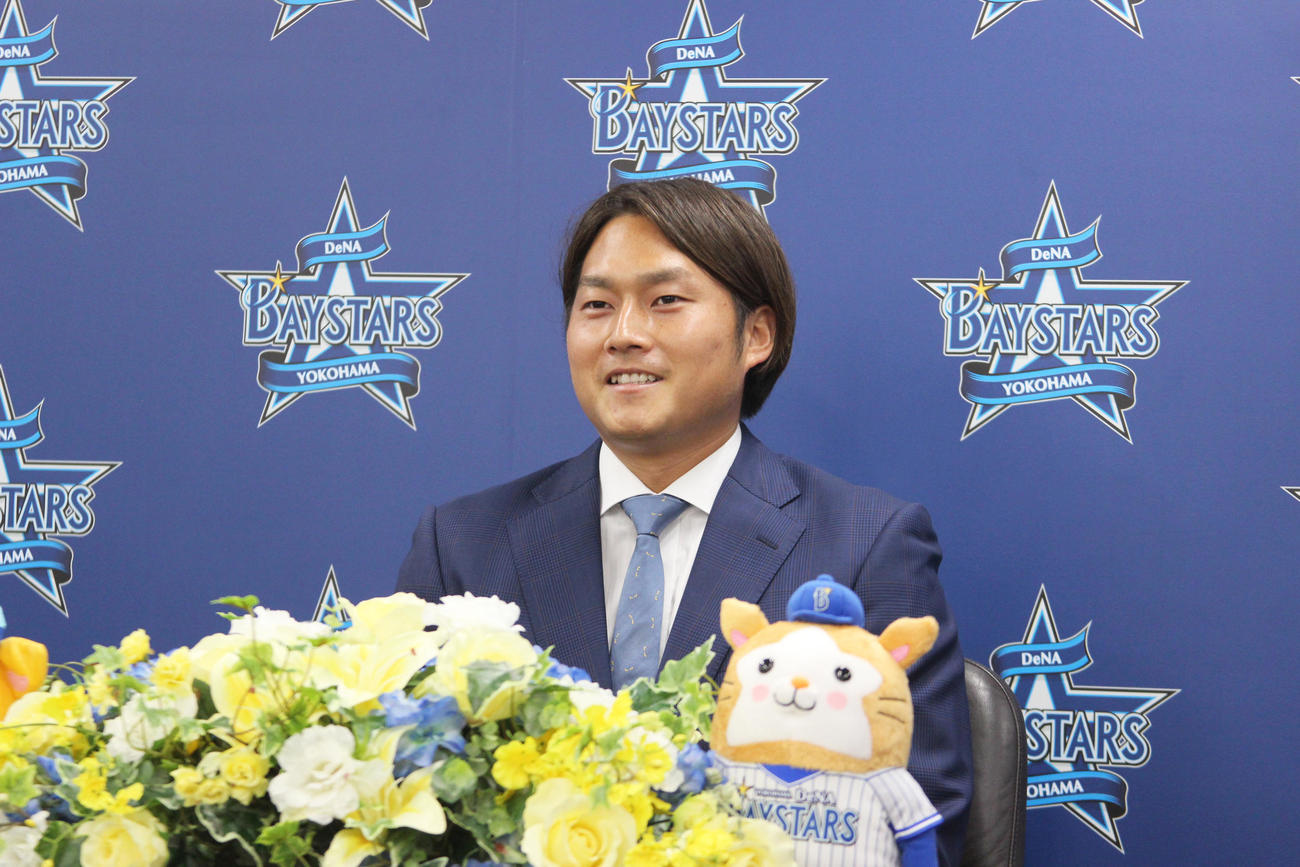 国吉との交換トレードでロッテからDeNAに加入した有吉は、入団会見で笑顔を見せる（球団提供）