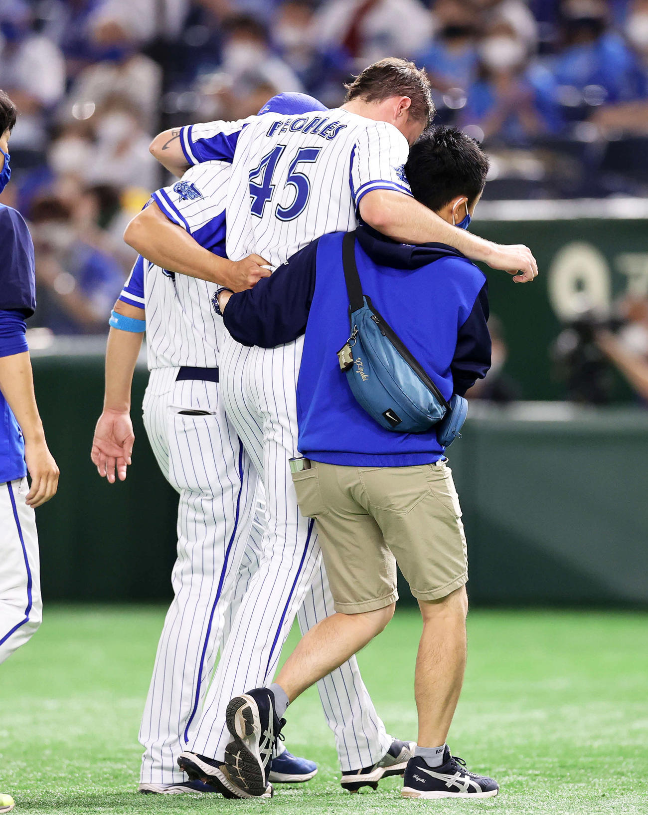 3回表広島無死一、三塁、DeNAピープルズは肩を借りてベンチに引き揚げる（撮影・鈴木正人）