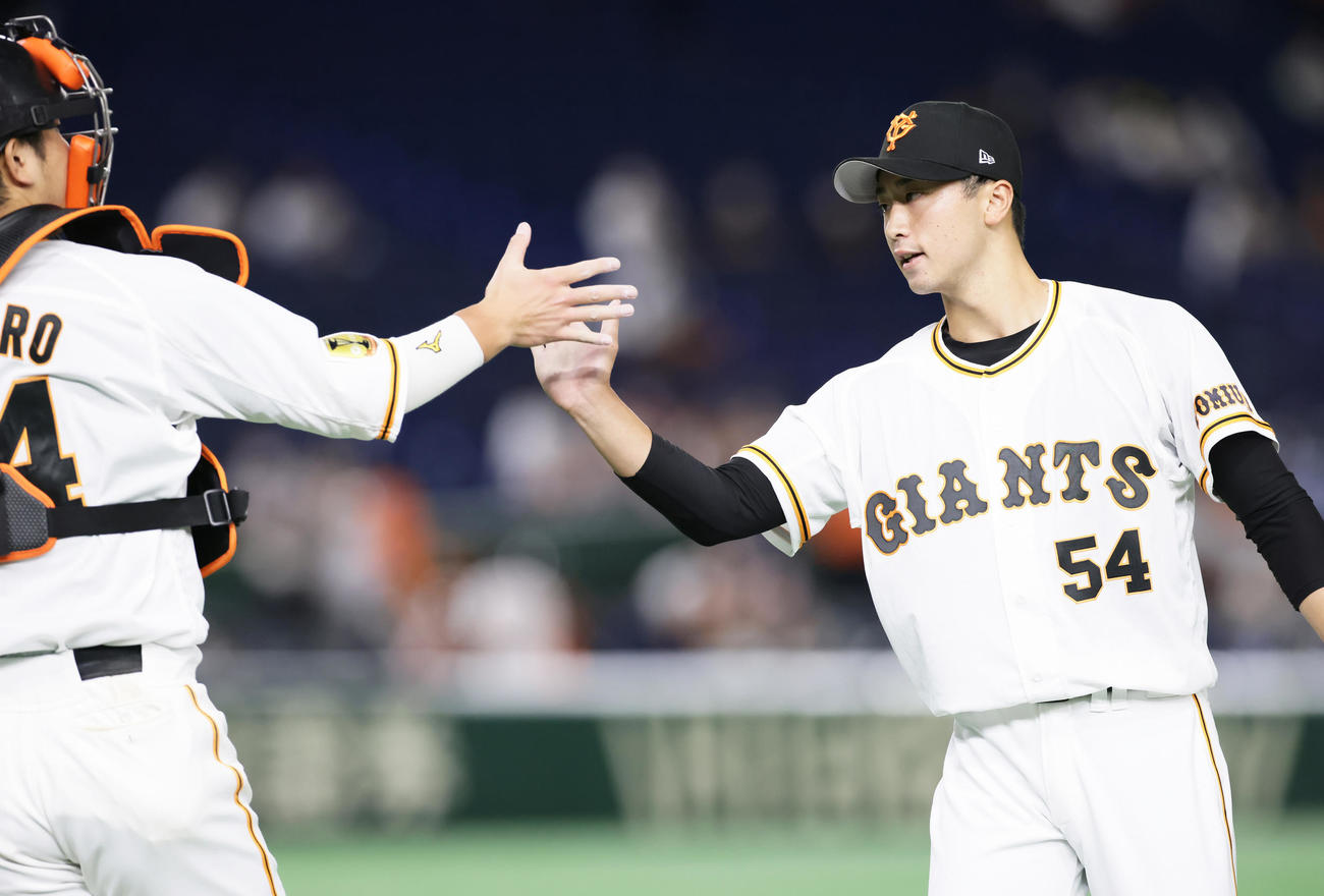 巨人対広島　勝利し、セーブを挙げた巨人直江（右）は大城とタッチを交わす（撮影・足立雅史）
