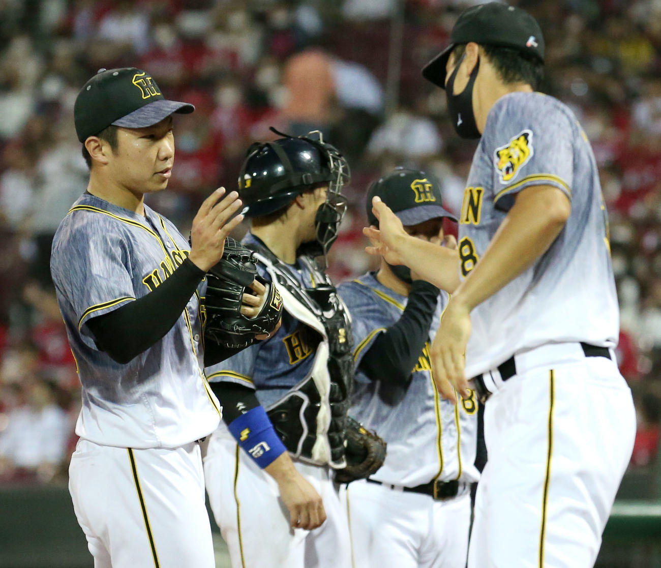 石井大（左）は5回を投げ終え佐藤輝（手前右）とタッチを交わす（撮影・上山淳一）