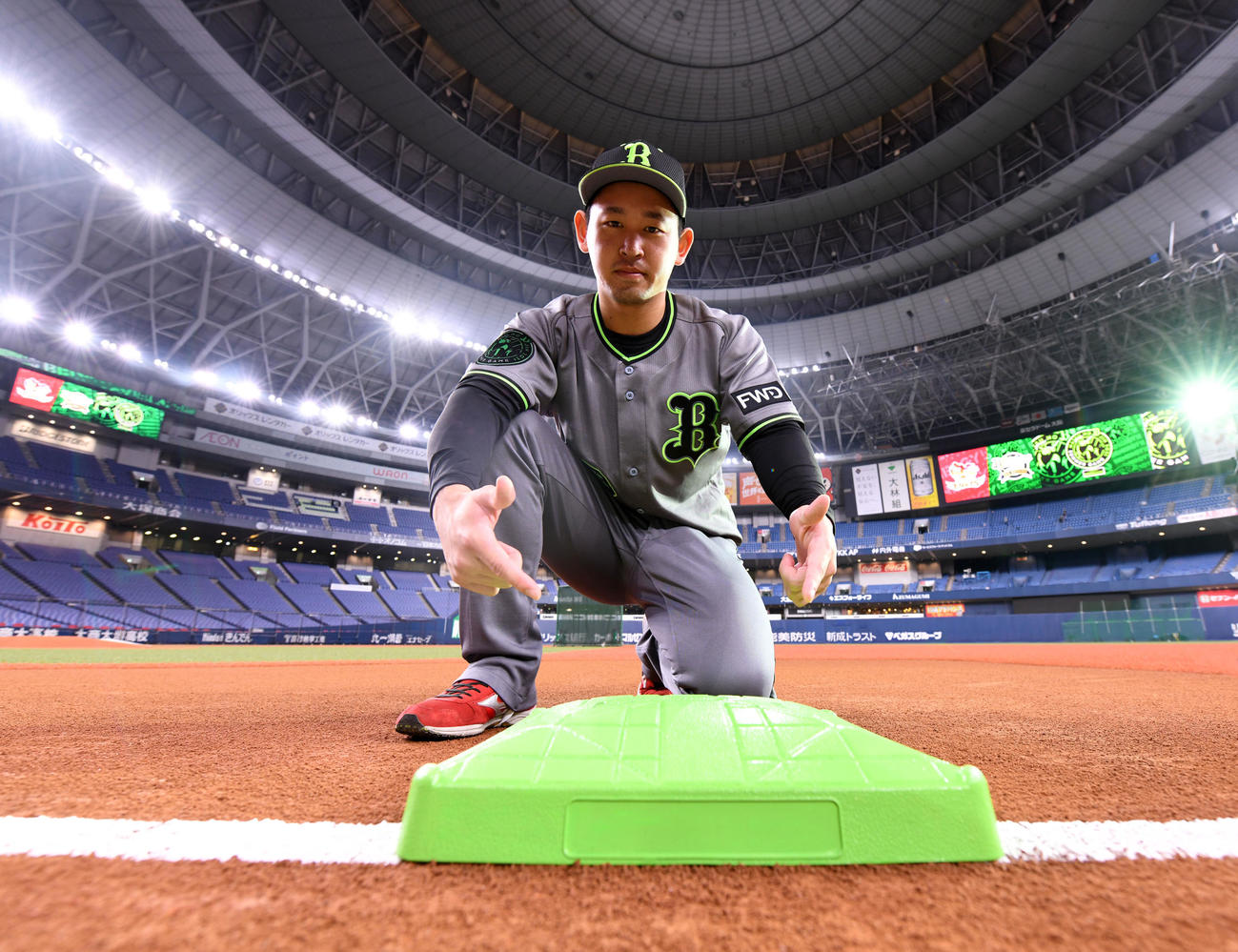 SDGs活動の象徴として使用するグリーンのベースを指さすオリックス宮城（球団提供）