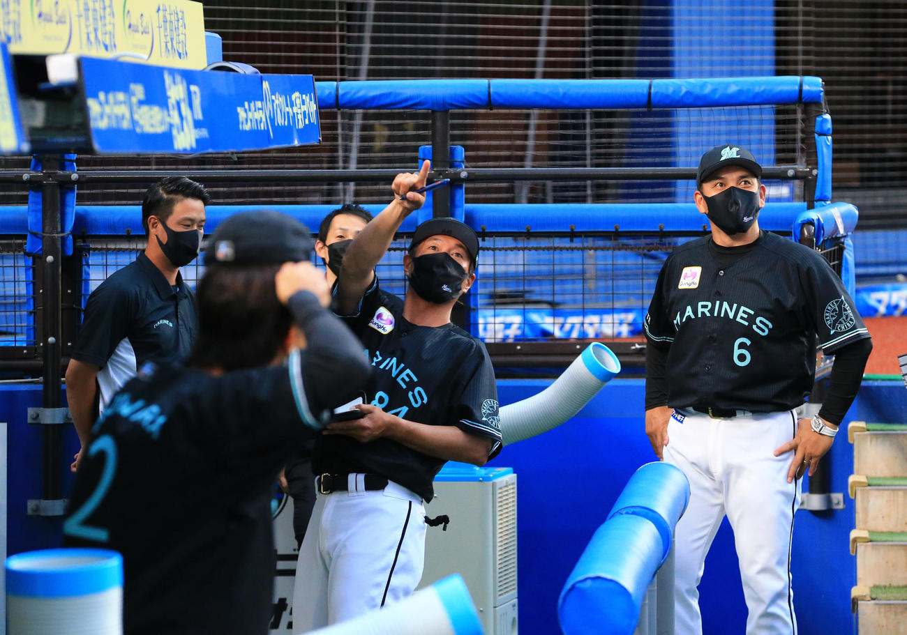 ロッテ対日本ハム　試合前、右翼後方から近づいてくる分厚い雨雲を見ながら心配そうな表情を見せるロッテ井口監督（右）（撮影・垰建太）