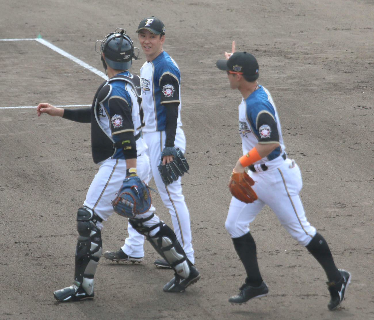 日本ハム対DeNA 6回表、269日ぶりに実戦登板を3者凡退で終えて笑顔の日本ハム斎藤（左は宇佐見、右は杉谷）（撮影・木下大輔）