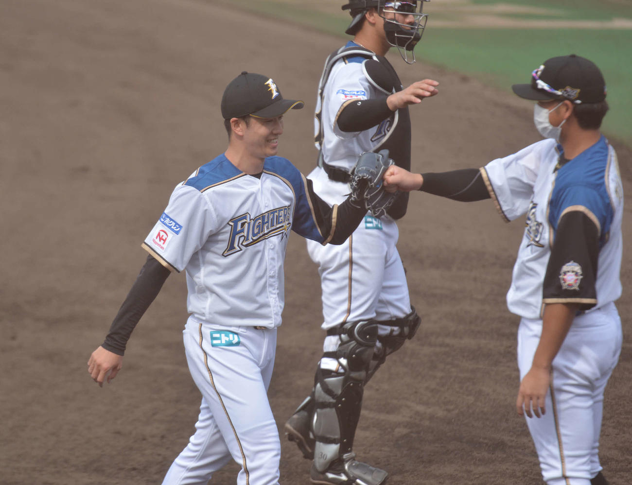 6回表、269日ぶりに実戦登板を無失点で終えた日本ハム斎藤は谷口（右）とグータッチ