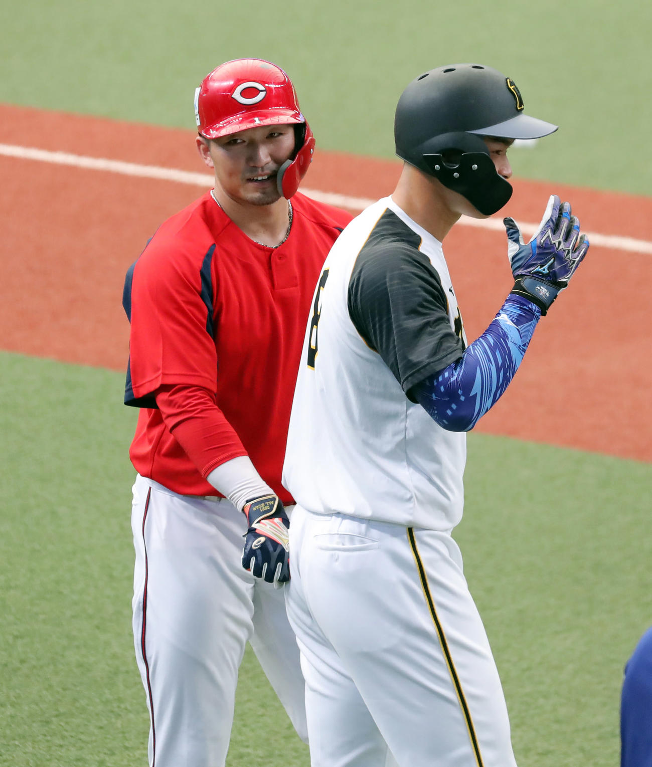 全パ対全セ　試合前、全セの鈴木（左）は打撃練習中、佐藤輝を尻をたたき鼓舞する（撮影・垰建太）