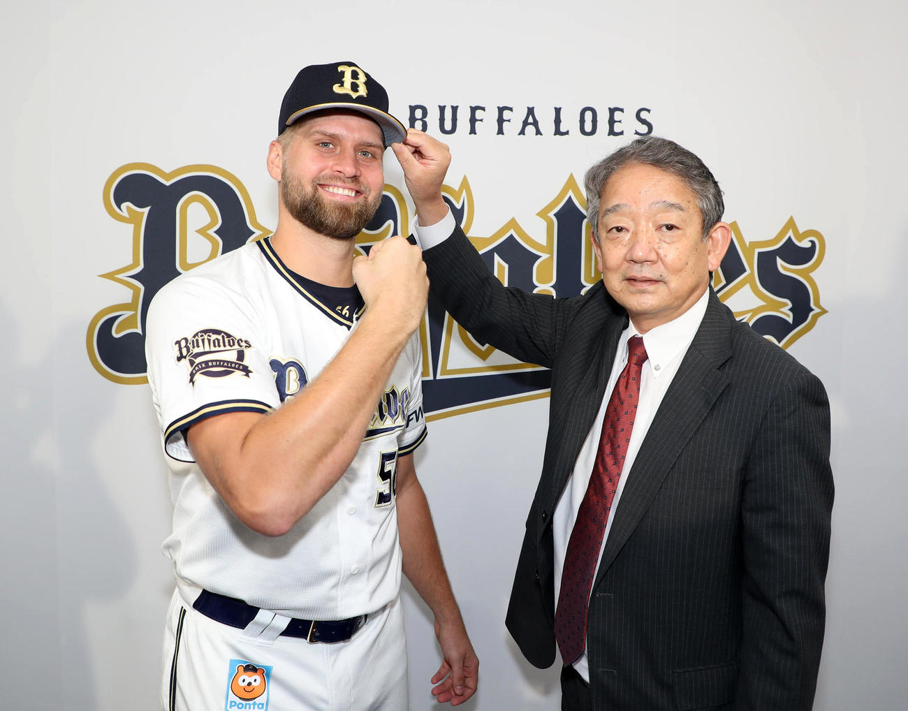 入団会見を行ったオリックスのスパークマン（左）は横田昭作国際渉外部長から帽子をかぶせてもらう