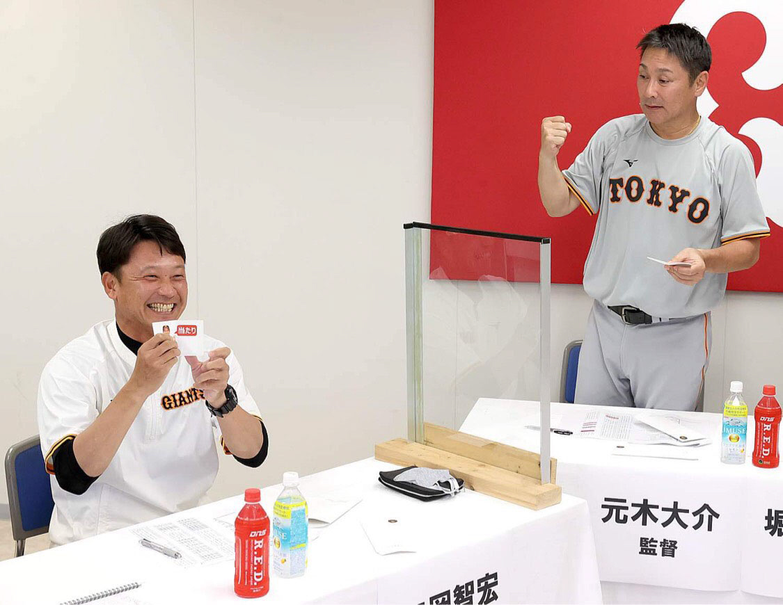 Gドラフト会議で当たりくじを引き、笑顔を見せる二岡3軍監督（左）。右は元木ヘッドコーチ（球団提供）