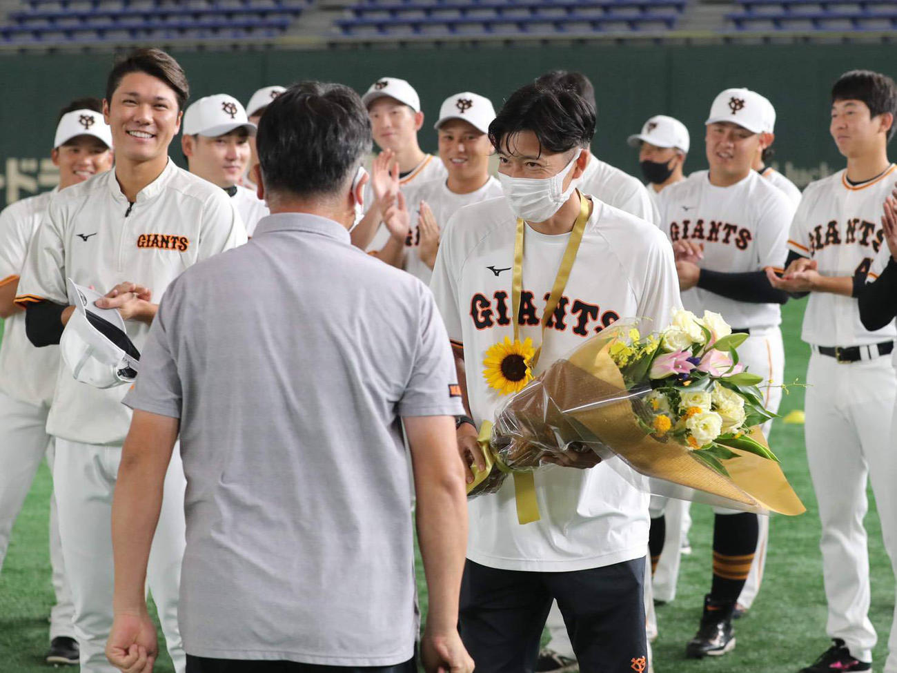 五輪後にチームに合流し、チームメートに祝福される根津トレーナー（右）。左は坂本（球団提供）