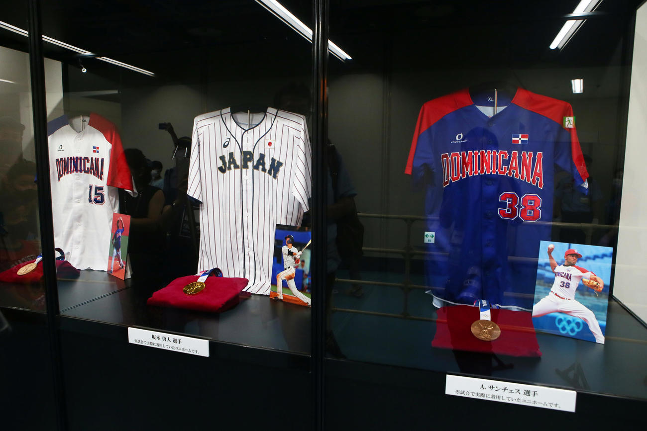 東京ドームに展示されている東京五輪のメダルとユニホーム。左から巨人のメルセデス、坂本、サンチェス（撮影・足立雅史）