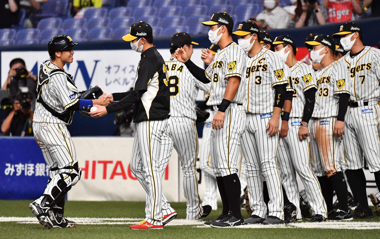 阪神対広島　阪神移籍後に初勝利した二保（左から2人目）は勝利球を手に梅野と握手を交わす（撮影・上田博志）