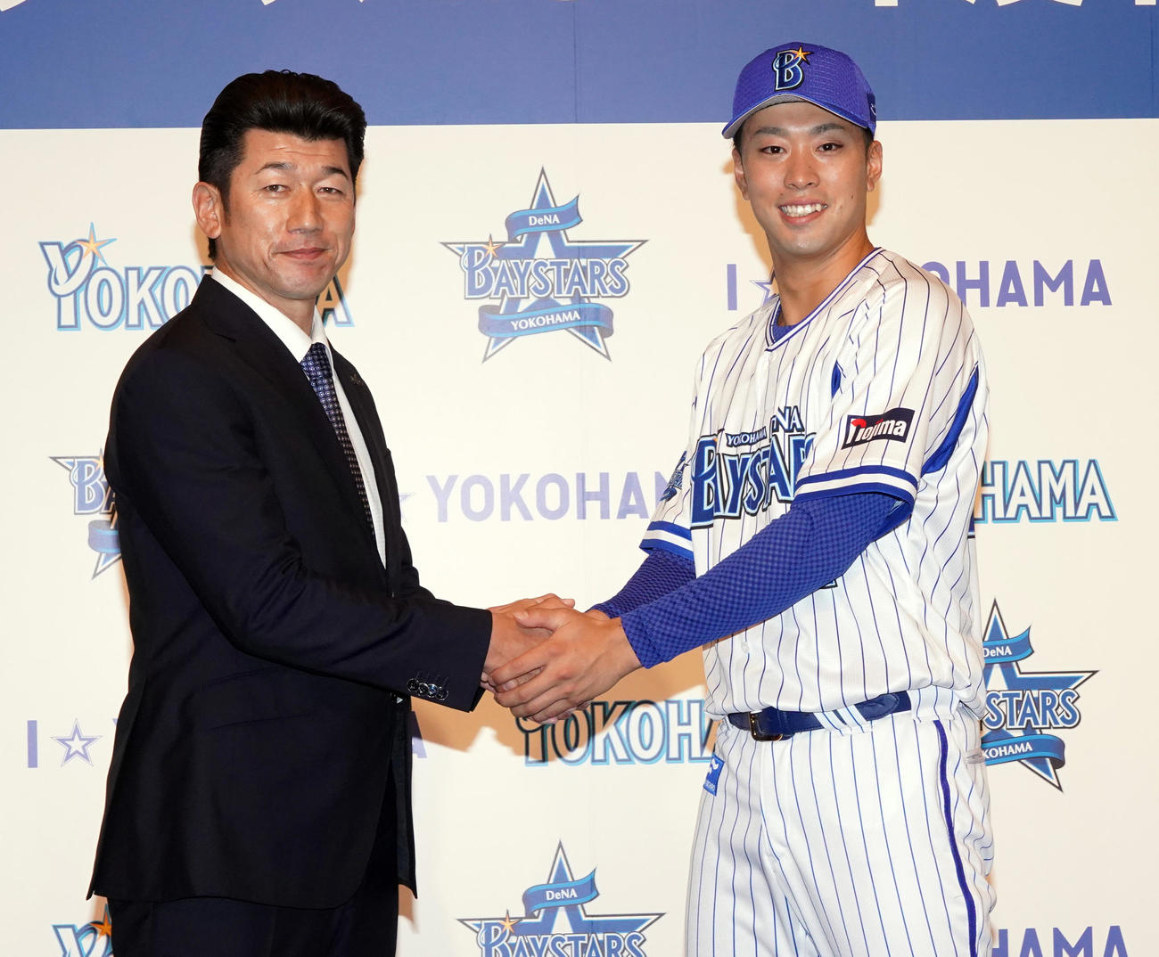 新入団会見でDeNA三浦大輔監督（左）と握手をかわすドラフト1位の明大・入江大生（2020年12月7日撮影）