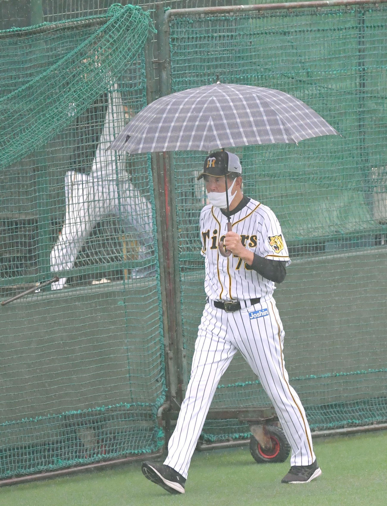 ウエスタン・リーグ阪神対中日　傘をさしてブルペン脇を歩く平田勝男2軍監督（代表撮影）2021年8月19日＝京セラドーム大阪