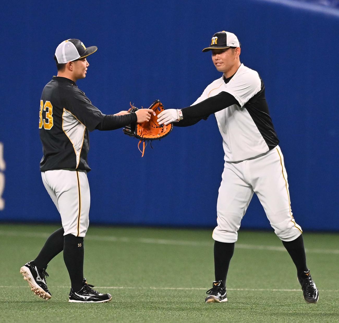中日対阪神　阪神原口（右）にファーストミットを借り一塁ノックを受ける糸原（撮影・上田博志）