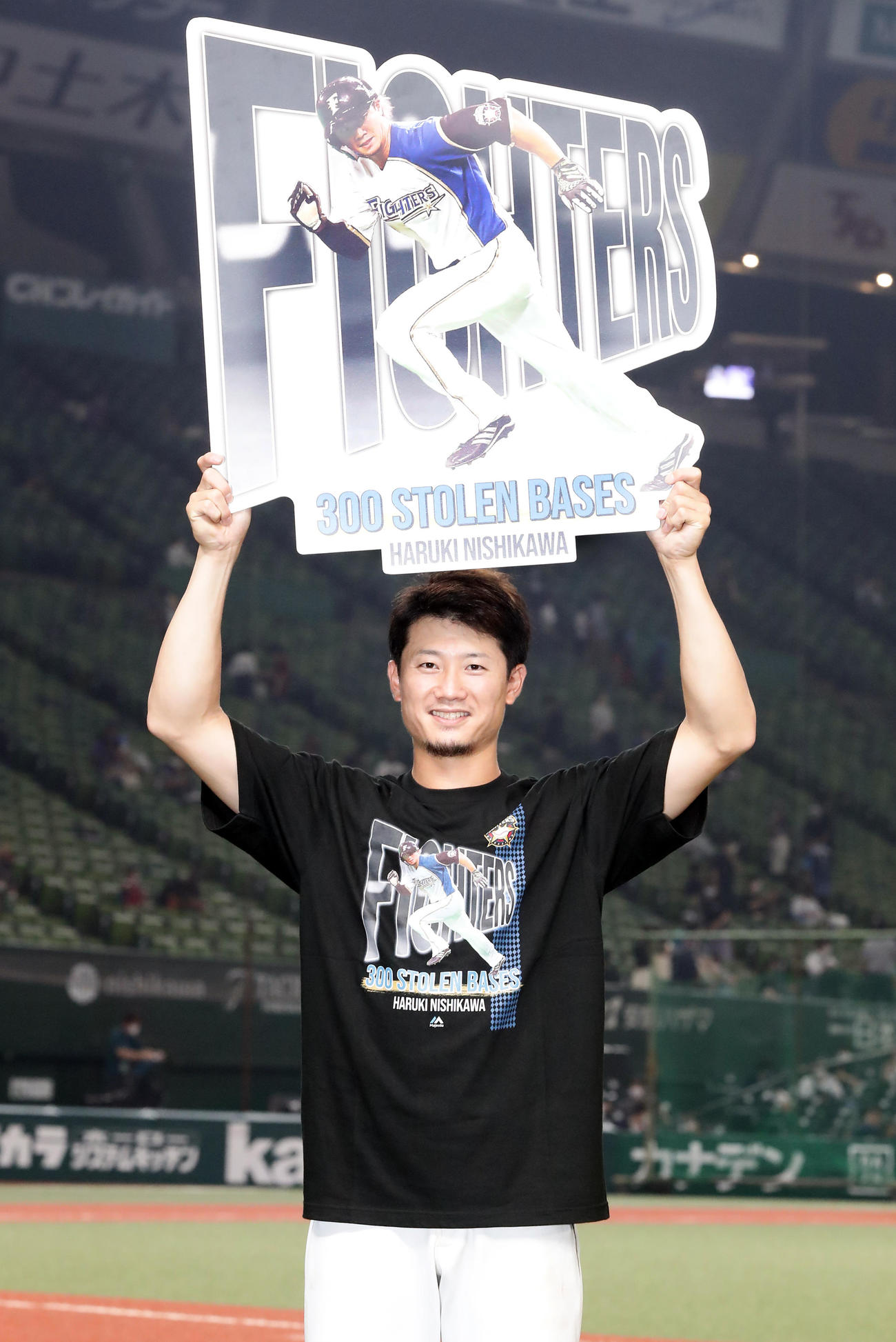 西武対日本ハム　300盗塁にボードを掲げ、記念Tシャツを着て笑顔を見せる西川（撮影・浅見桂子）