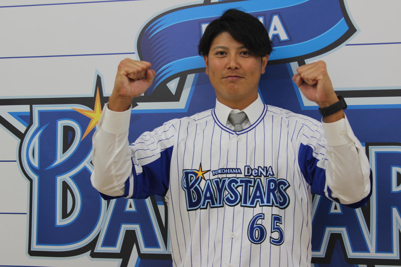 支配下選手契約を結んだDeNA宮国は背番号「65」のユニホームを着てガッツポーズ（球団提供）